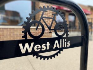 A West Allis bike rack that shows a bike gear, a bike and a the words West Allis
